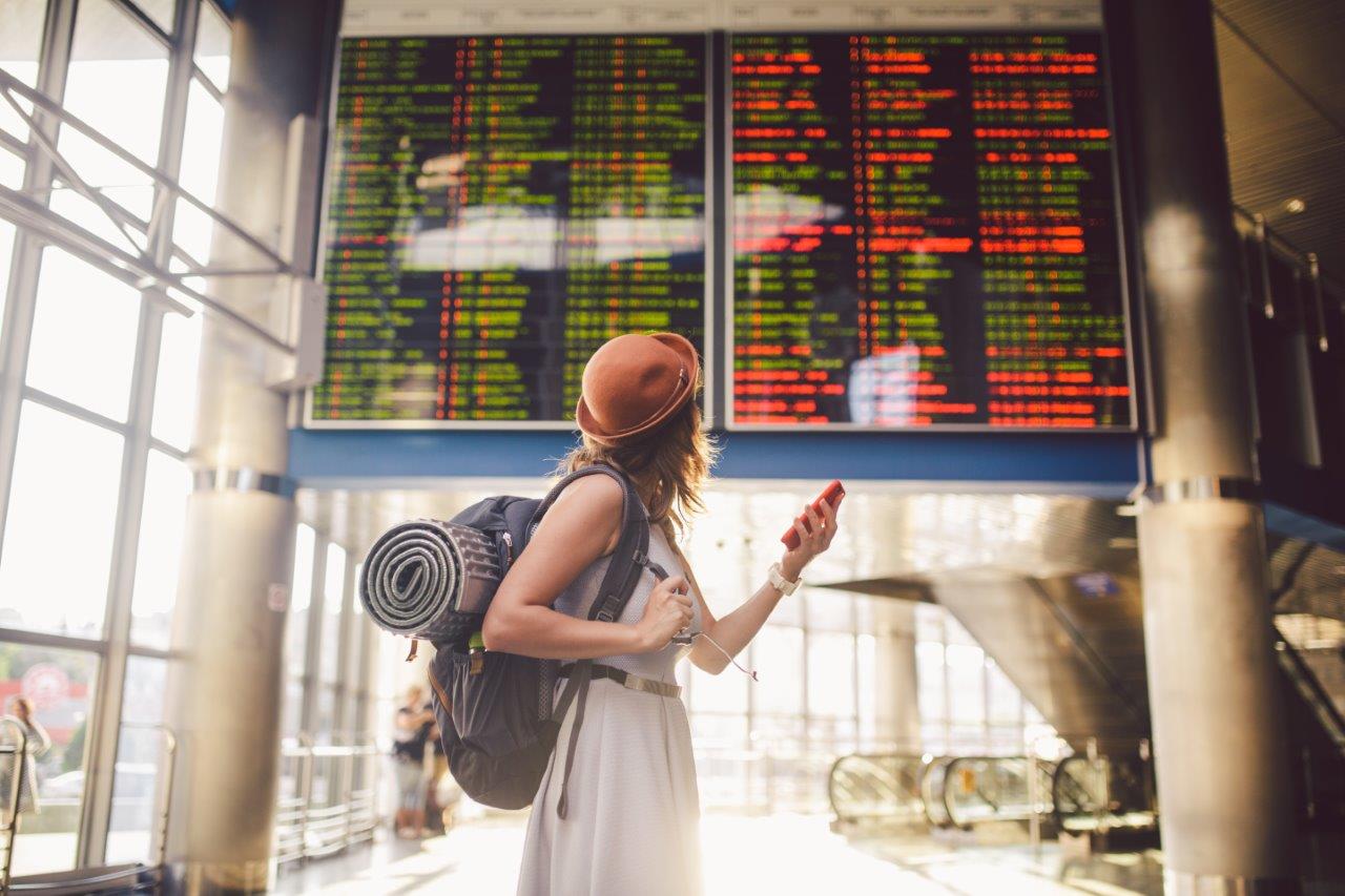 Une femme regarde le tableau d'affichage des vols dans un aéroport