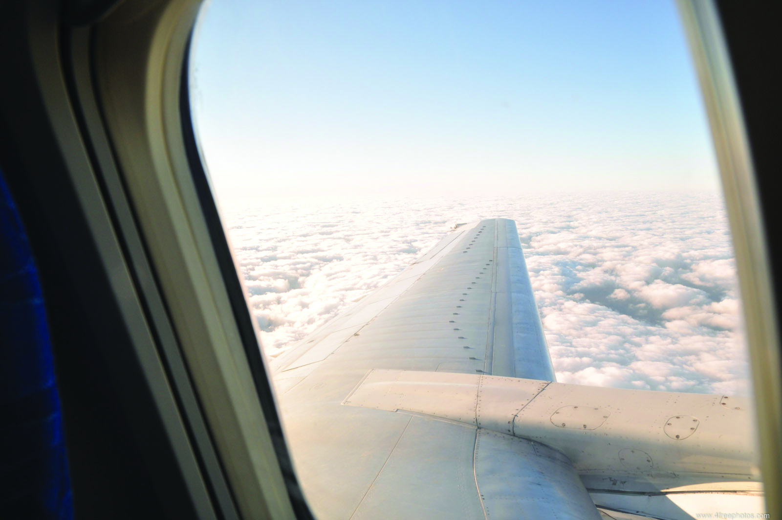 Vue sur l'aile d'un avion survolant les nuages, depuis le hublot de l'avion