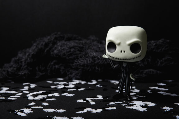A skeletton figurine with a creepy smile in a dark background