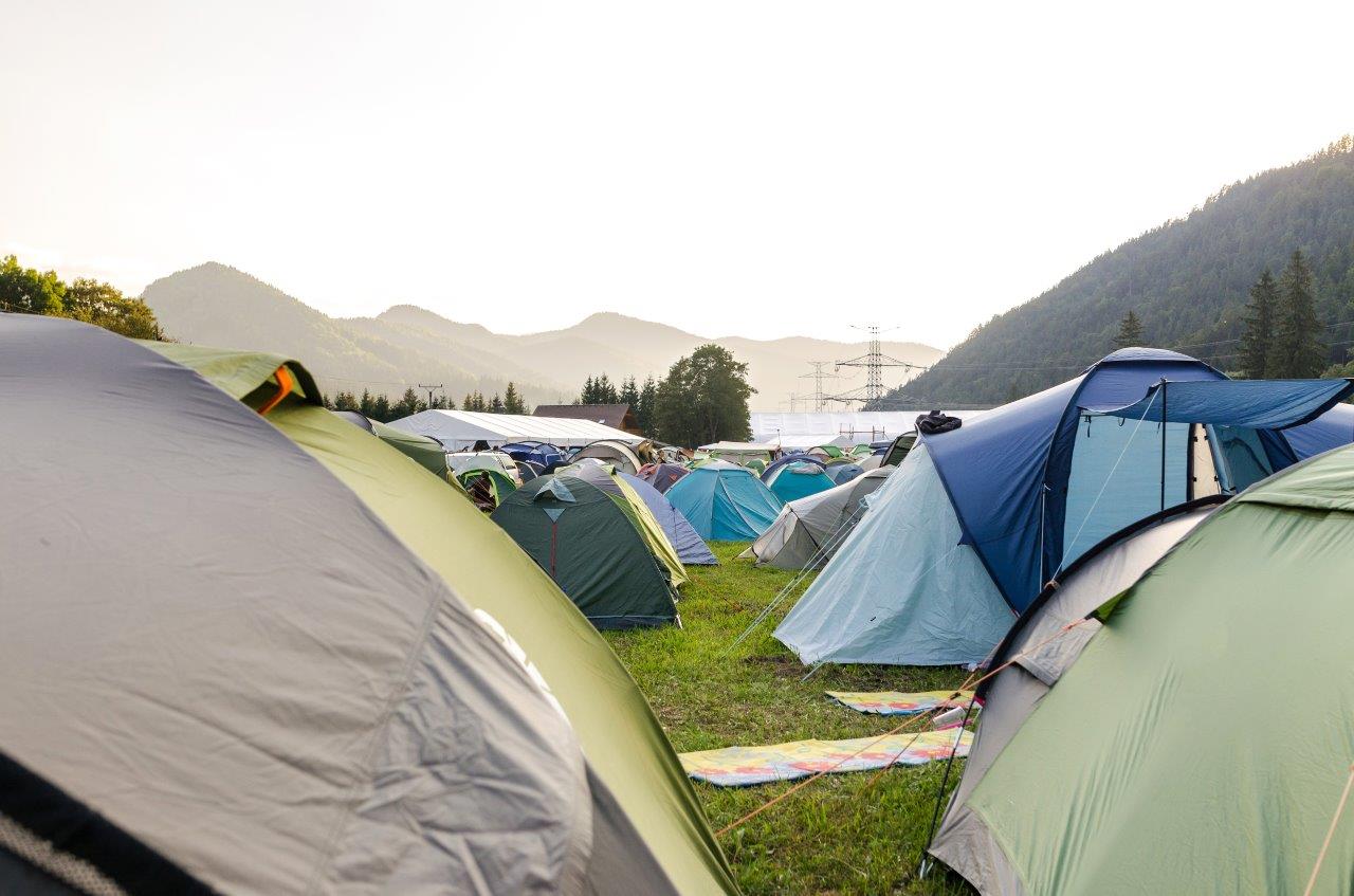 Several tents in a field, with the mountains in the background