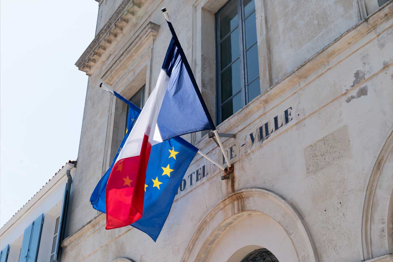 Un drapeau français et un drapeau européen accroché à la façade d'un hôtel de ville
