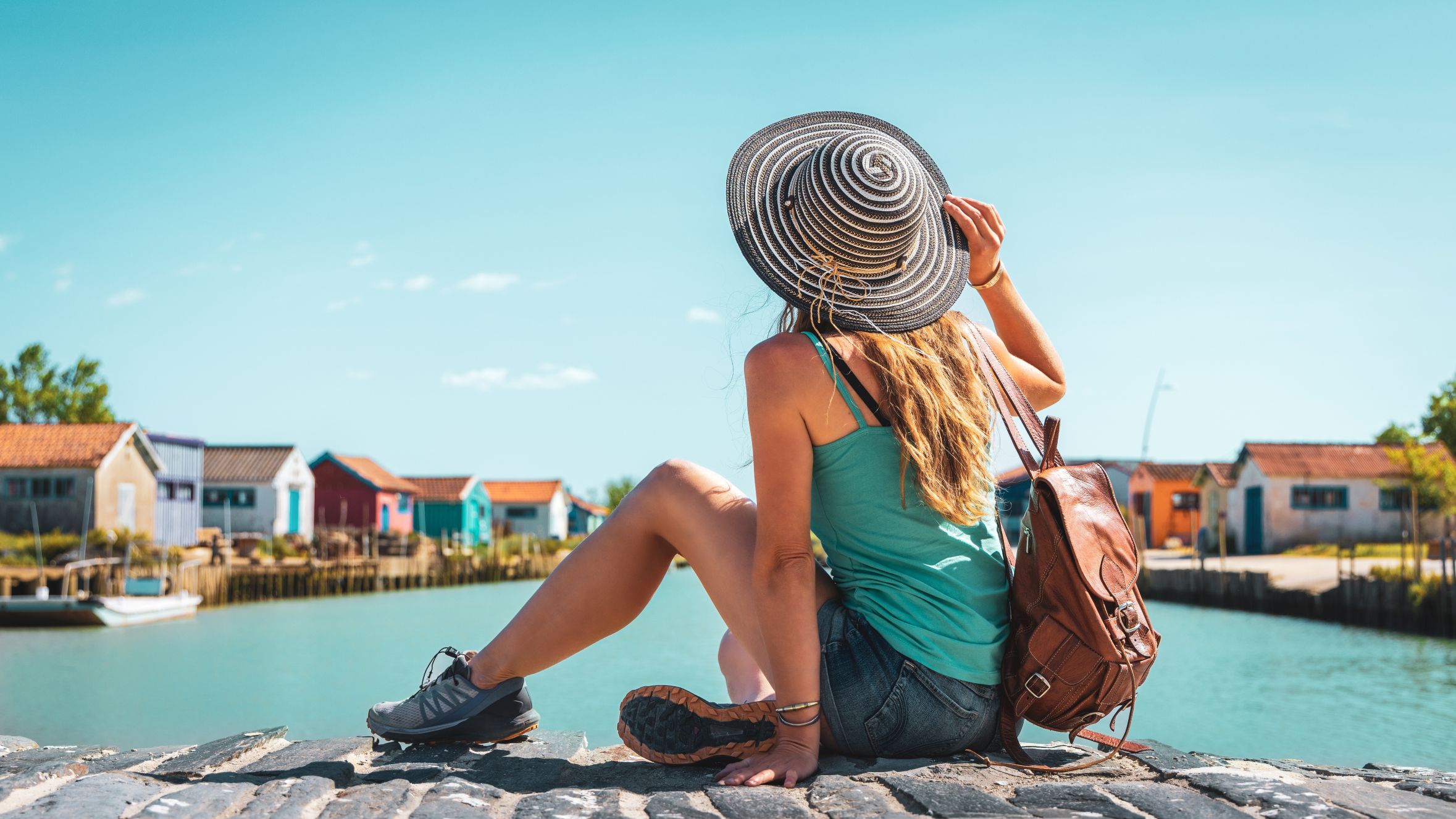 Une femme de dos regardant un canal avec des maisons colorées