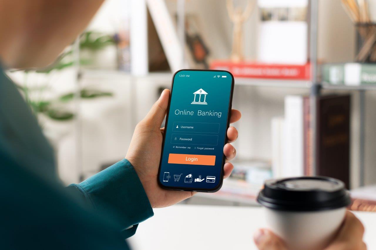 Une personne tient en main son téléphone sur lequel est affiché une application bancaire
