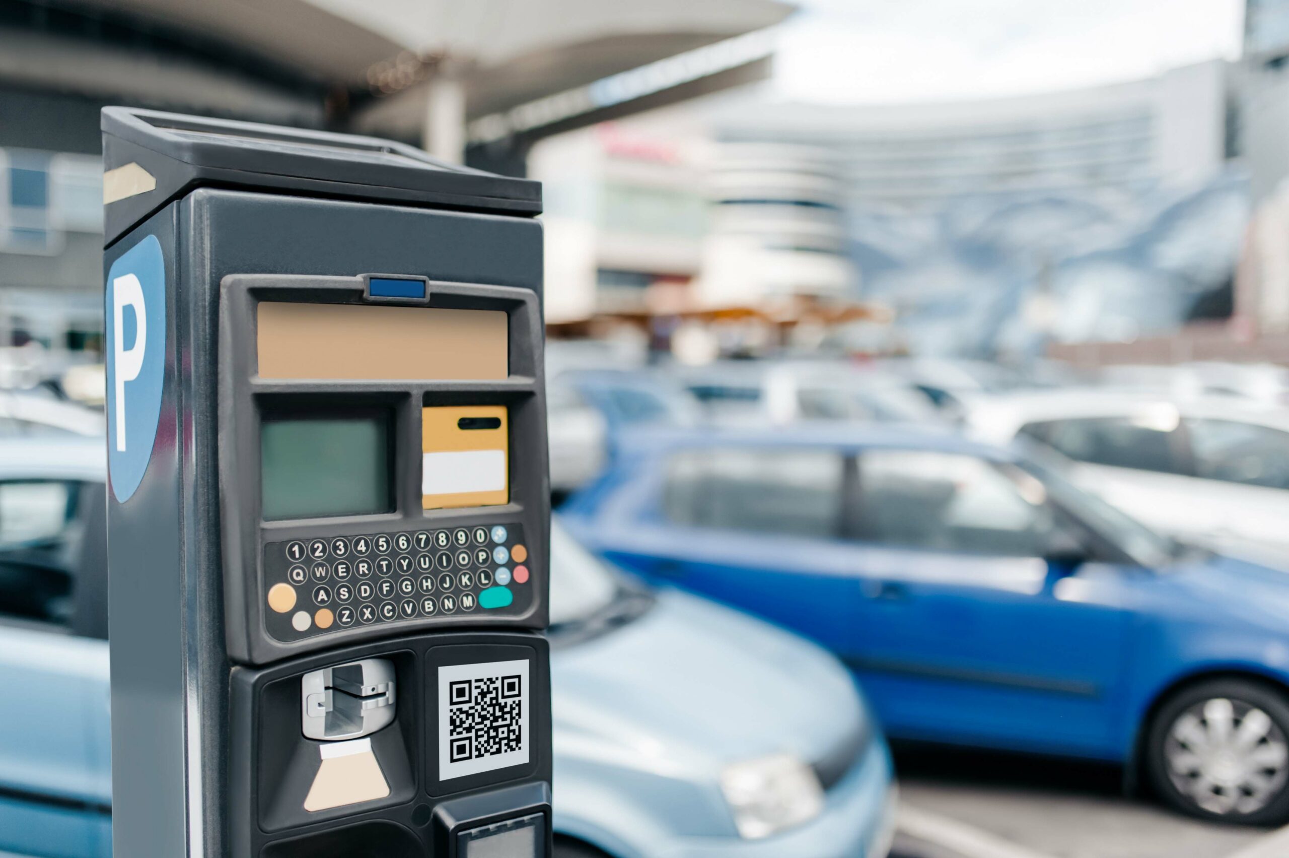 A parking ticket machine with blurred cars in the background