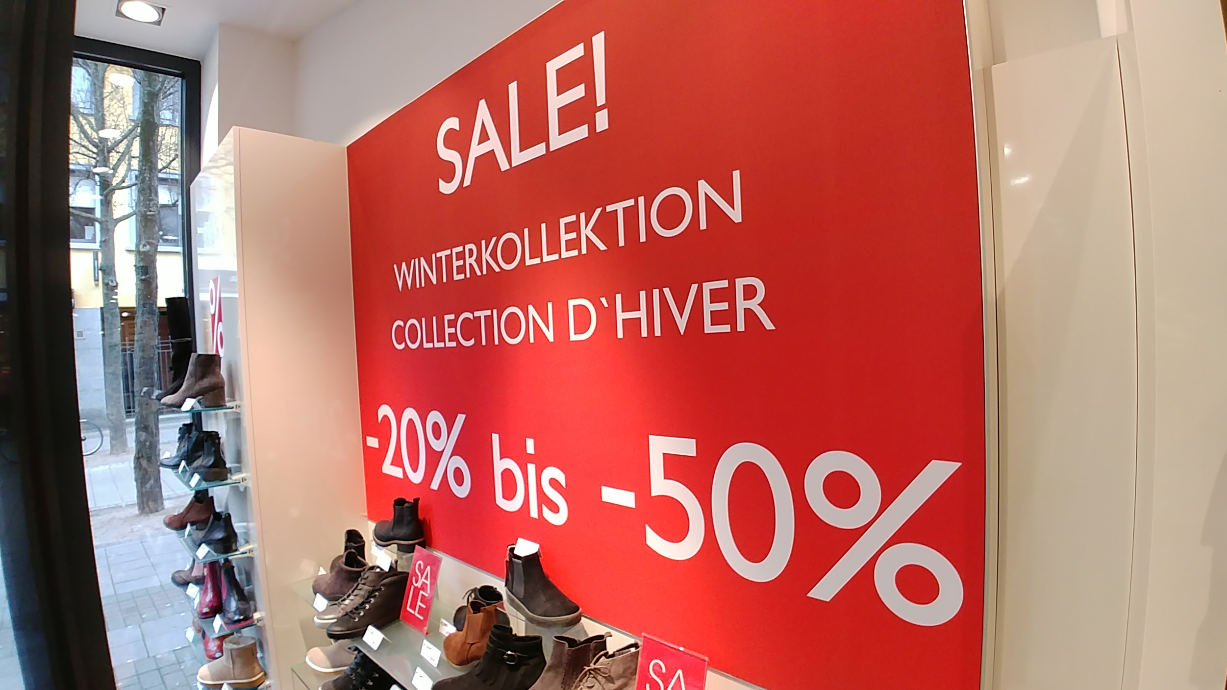 Intérieur d'une boutique de chaussures, où une affiche avec un pourcentage indique les soldes