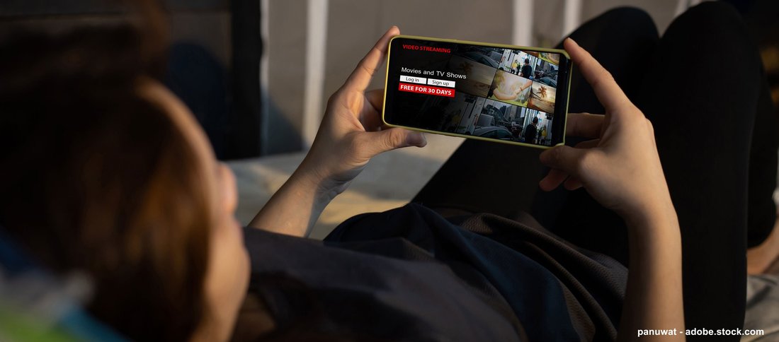 A person lying on their back is accessing streaming services on their phone