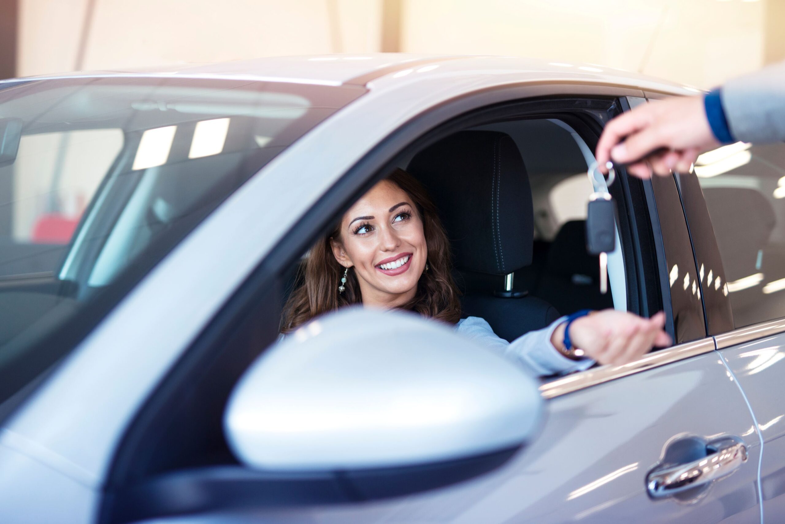 A woman in a car being handed a set of keys