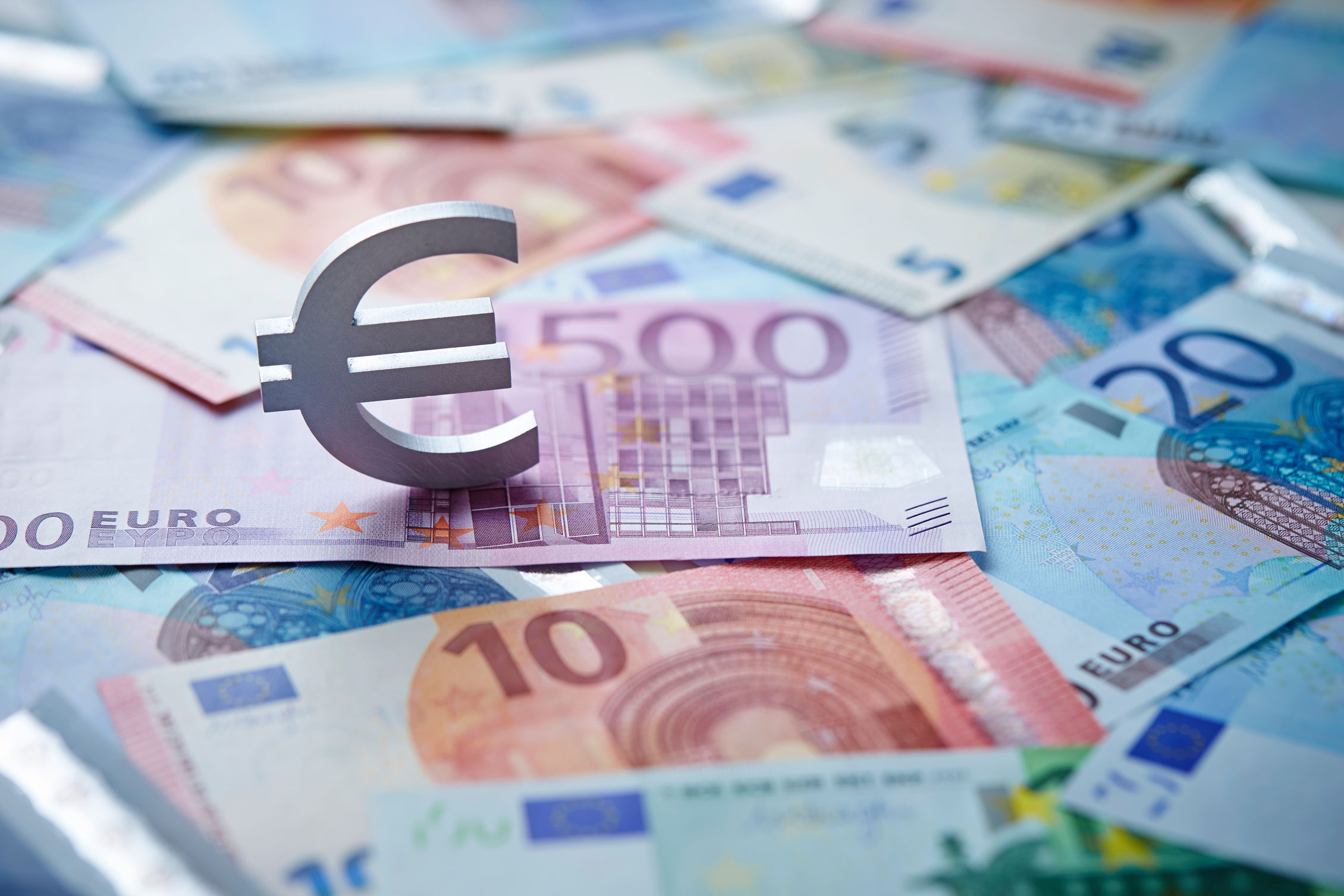 Le symbole euro posé sur des billets en euros éparpillés