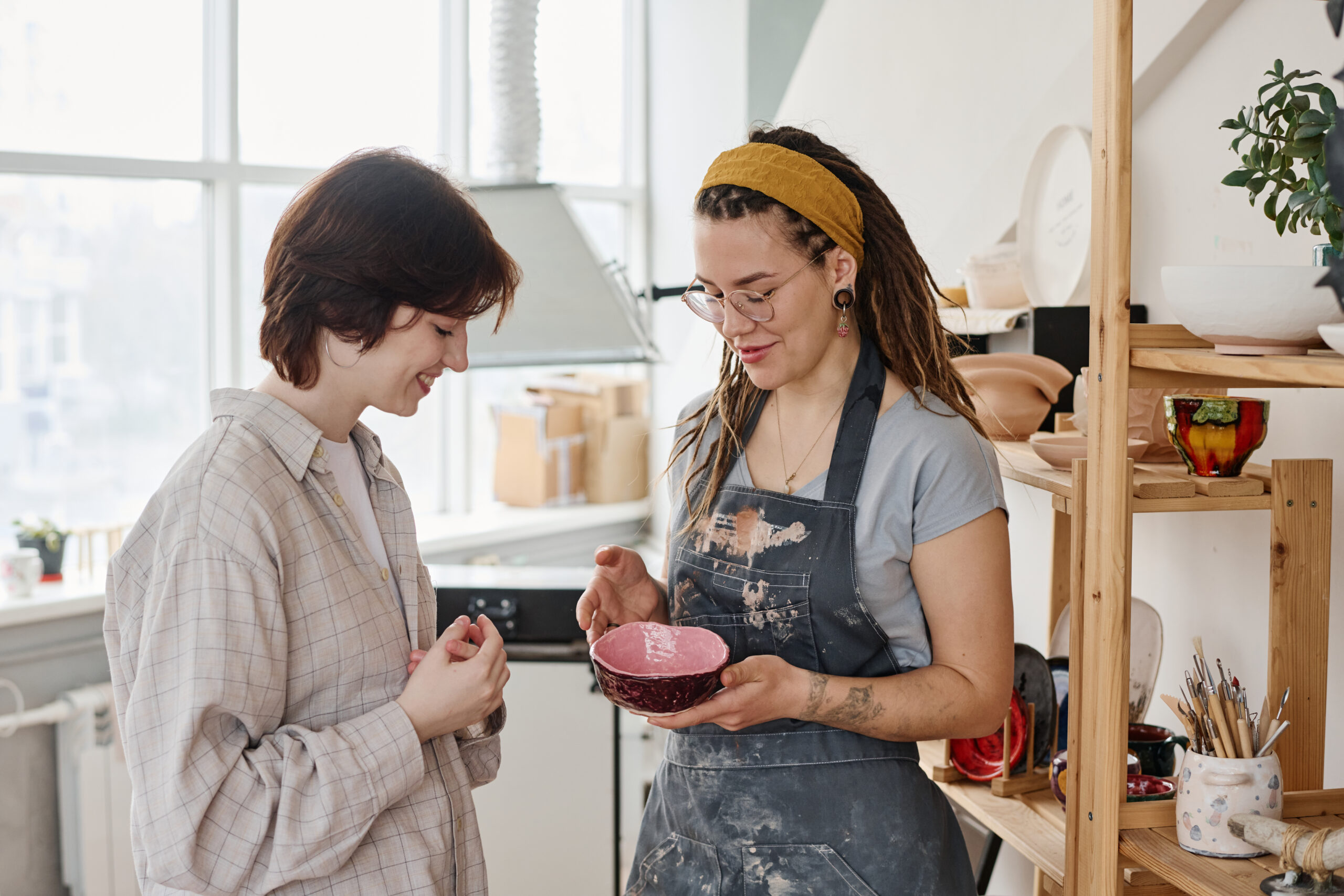 A craftswoman shows a delighted customer one of his ceramic pieces.