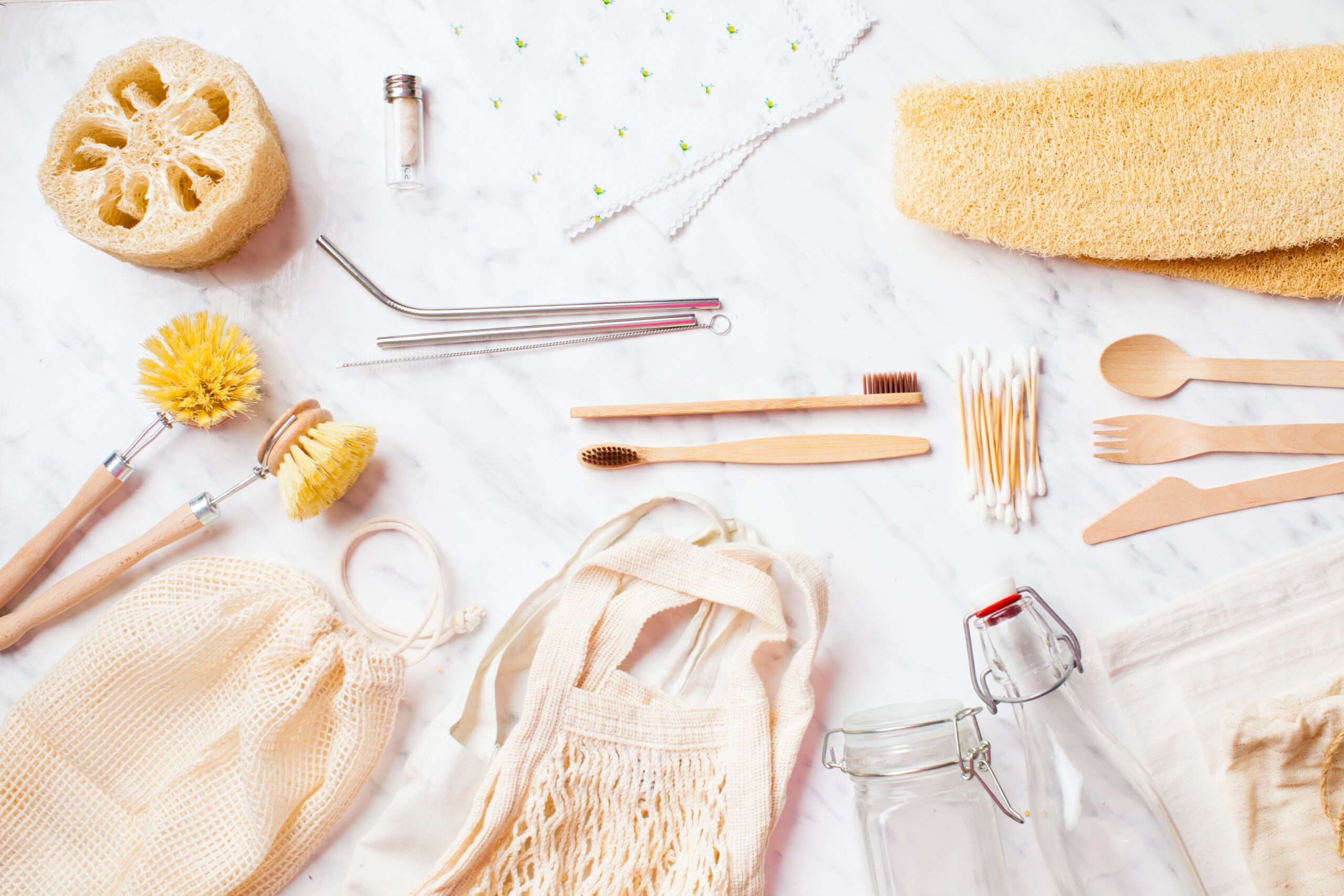 A set of zero-waste items: stainless steel straws, dish brushes, reusable bags, glass bottles, bamboo toothbrushes