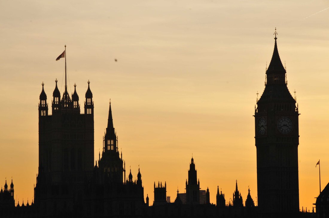 Vue des silhouettes du parlement de Londres et de Big Ben à travers un coucher de soleil.