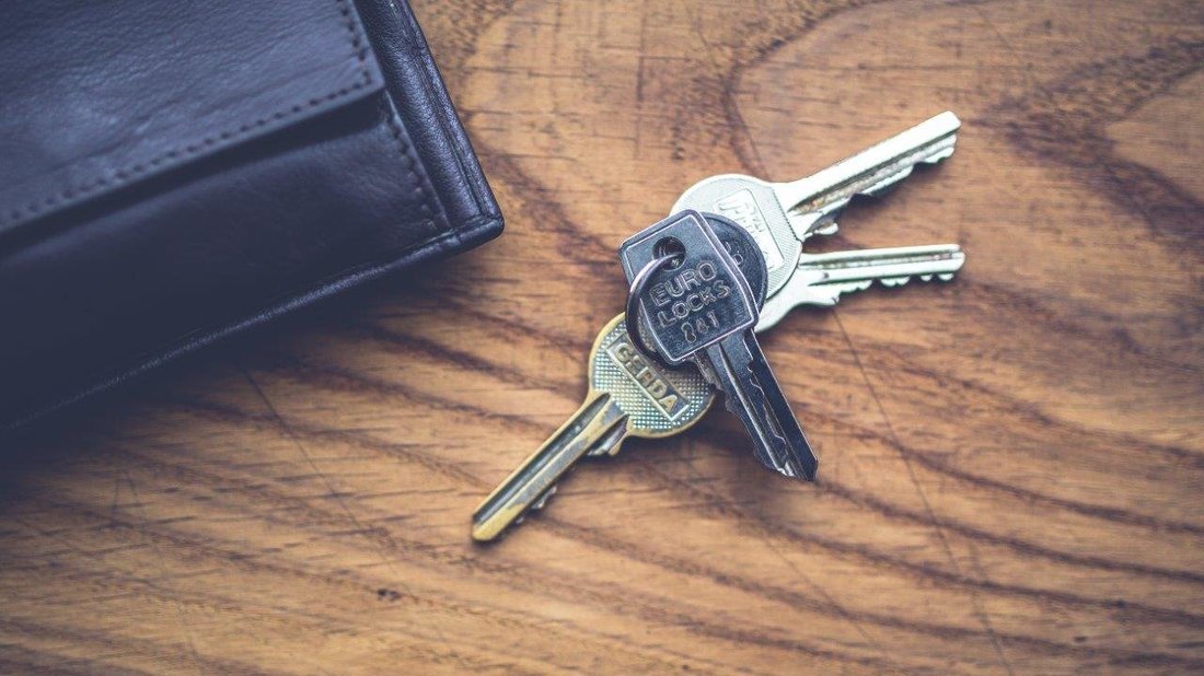 A bunch of keys is placed on a wooden space.