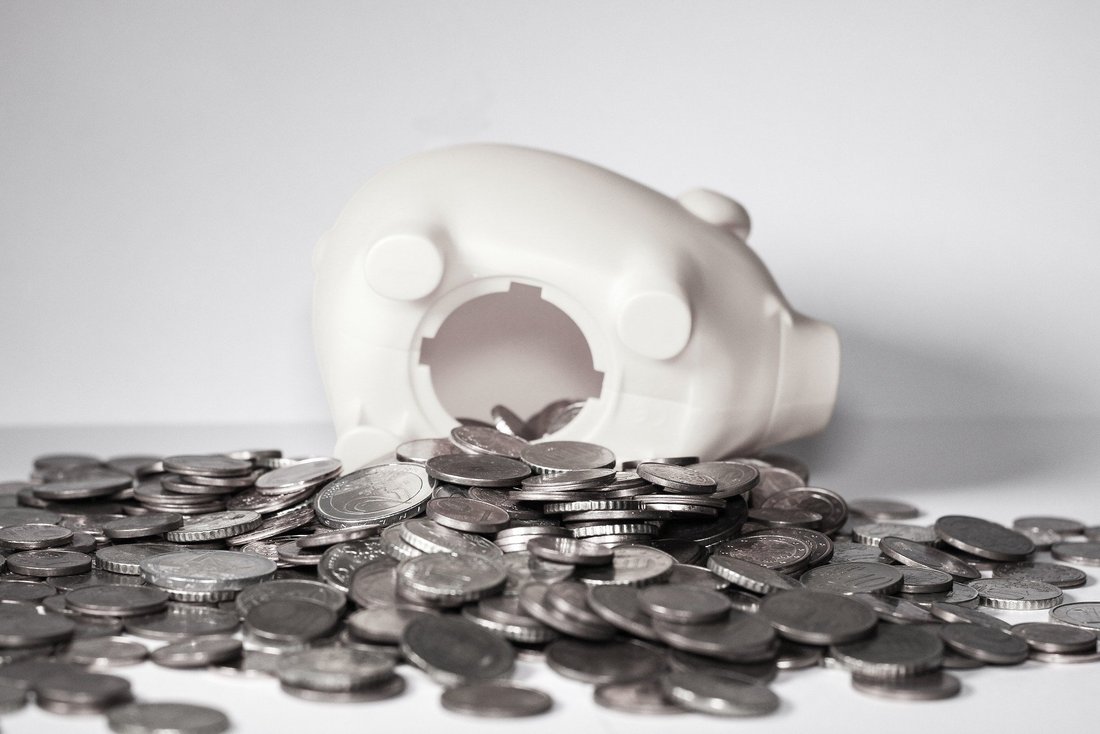 tirelire-economie-investissement.jpg Une tirelire en forme de cochon est ouverte et de nombreuses pièces de monnaies sont étalées tout autour.