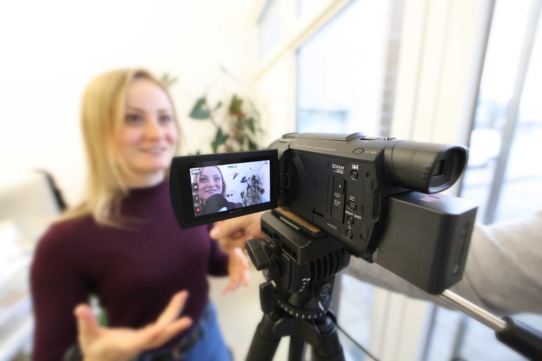 A woman speaks in front of a camera that is filming.