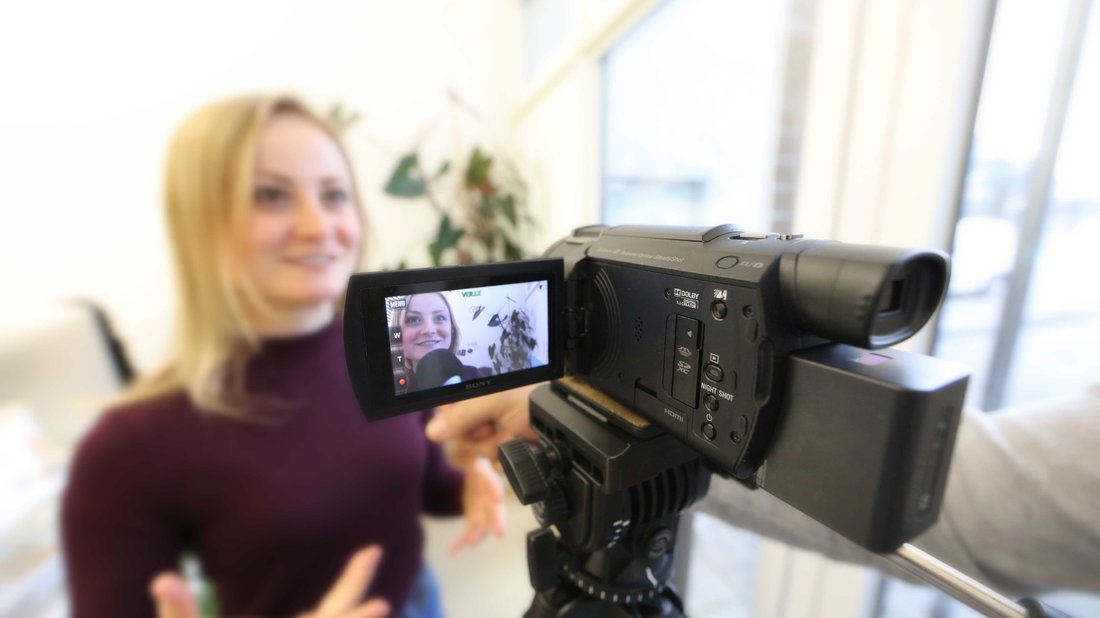 A woman speaks in front of a camera that is filming.