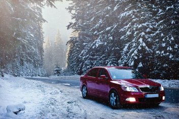 A car driving through a forest on a snowy road