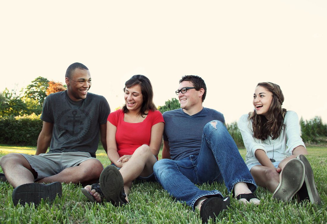 sourire de jeunes femmes et hommes assis sur l'herbe