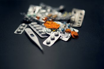 A bunch of medicine pads and a thermometer on a black background.