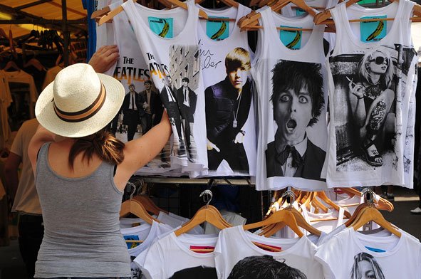 A woman looks at T-shirts at a market stall.