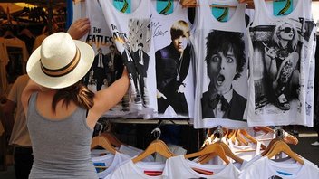 Une femme regarde des t-shirts sur un stand de marché.