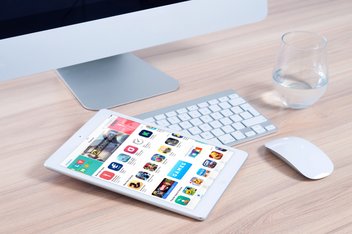 A computer and a tablet with the screen on on a desk.