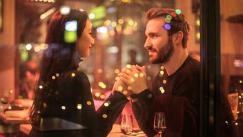 Couple qui se tient les mains amoureusement à une table de restaurant.