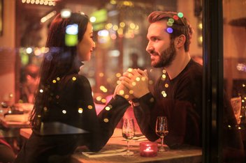 Couple holding hands lovingly at a restaurant table.