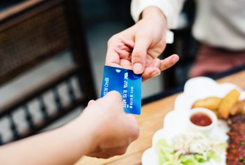 One person gives their credit card to another to make a payment.
