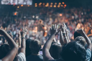 Une foule de personnes lève les mains dans un évènement.