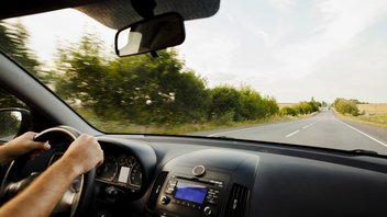 Une personne au volant de sa voiture sur une route de campagne vide.