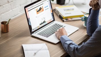 Un homme en chemise regarde une page Internet sur son ordinateur portable.