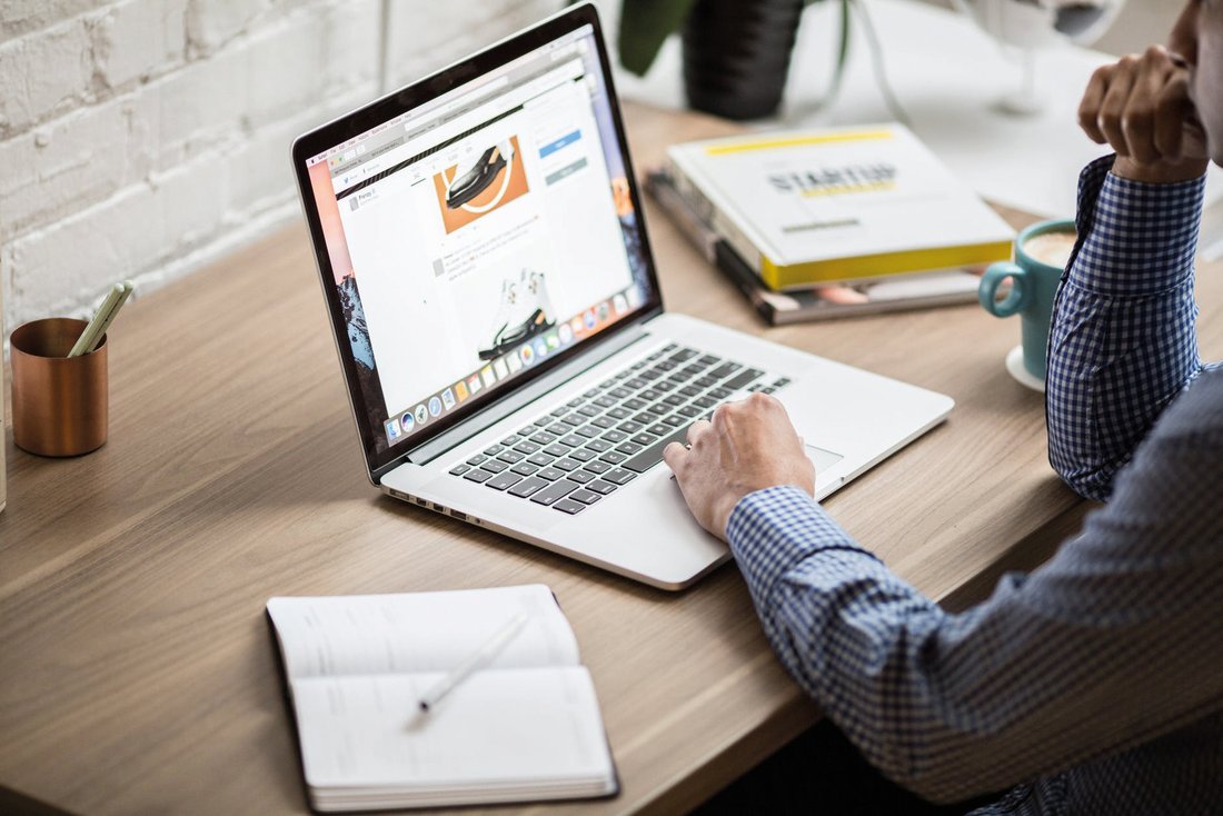 A man in a shirt is looking at a web page on his laptop.