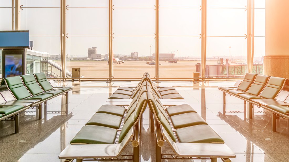 A boarding room with a view of the runway in the background.