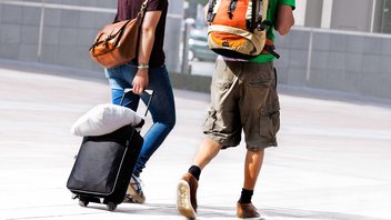 Deux personnes marchent avec leurs sacs à dos et une valise.