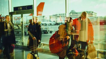 Des voyageurs font la queue avec leurs bagages au niveau d'une porte d'embarquement dans un aéroport.