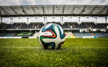 A football on the lawn of a stadium.