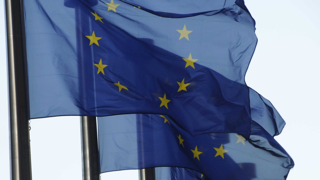 Trois drapeaux européens alignés flottent dans le vent.