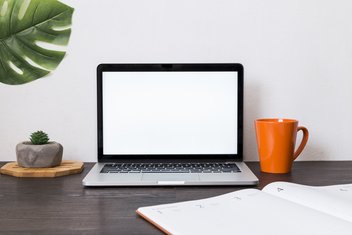 View of a workspace with a laptop, an agenda, a mug.