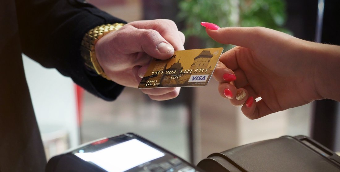 A man gives his bank card to a woman who holds a bank terminal for payment.