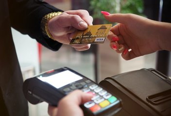 Un homme donne sa carte bancaire à une femme qui tient un terminal bancaire pour le paiement.