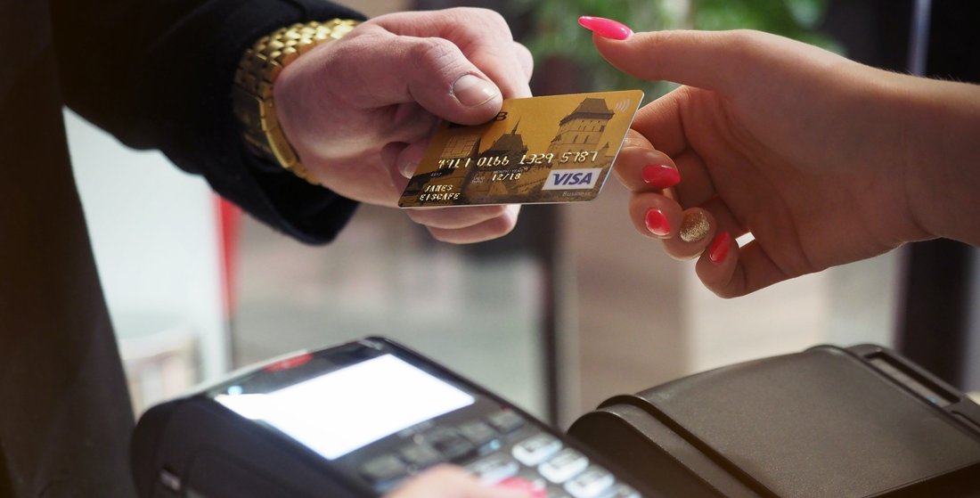 Un homme donne sa carte bancaire à une femme qui tient un terminal bancaire pour le paiement.