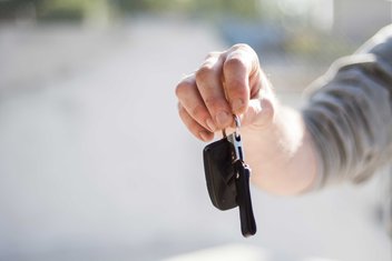 A person's hand holds out car keys.