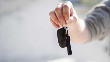 La main d'une personne tend des clés de voiture.